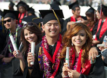CSUEB graduates holding their diplomas at a commencement ceremony.