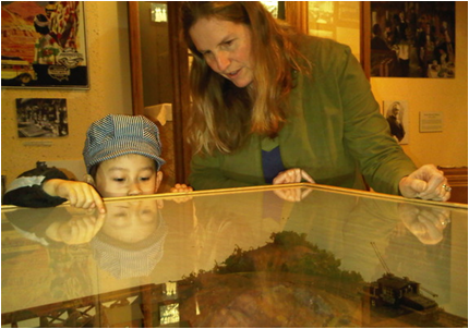 Marjorie Rhodes-Ousley helps Kenji, 4, look at a model railroad display