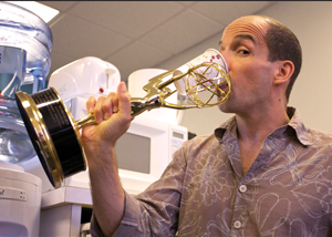 JR Havlan drinks from a paper cup inserted in one of his Emmy statues.